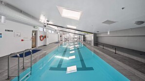 Ein Schwimmbecken mit deutlichen Bahnen, einem Rettungsschwimmerstuhl und einem Hinweisschild für den Ausgang.