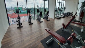 A gym with various exercise equipment, large windows, and a view of a cityscape. - 90309 Kozi Square (Kuching)