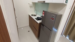 A compact kitchen with a refrigerator, sink, and wooden cabinets. - 90309 Kozi Square (Kuching)