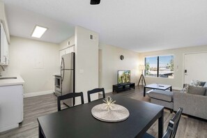 A modern living room with a dining table, sofa, and TV.