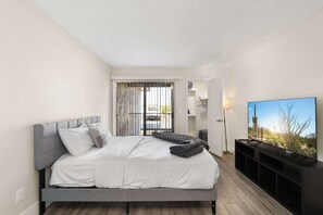 A bedroom with a bed, a TV, and a view of a balcony. - 2BR Modern Mesa Stay Near DT with Pools & Gym (Mesa)