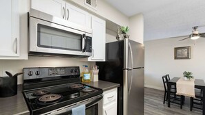 A modern kitchen with stainless steel appliances, white cabinetry, and a dining area with a table and chairs.