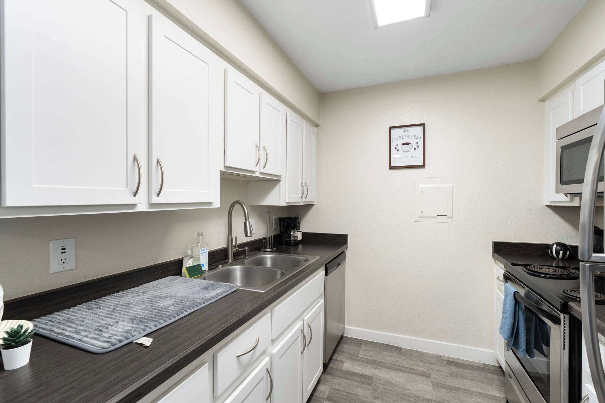 A modern kitchen with white cabinets, stainless steel appliances, and a gray countertop.