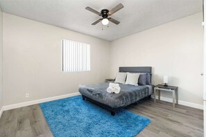 A bedroom with a bed, a ceiling fan, a window, a nightstand, and a blue rug. - 1BR Charming Mesa Stay, Sleeps 2, Near Downtown (Tempe)