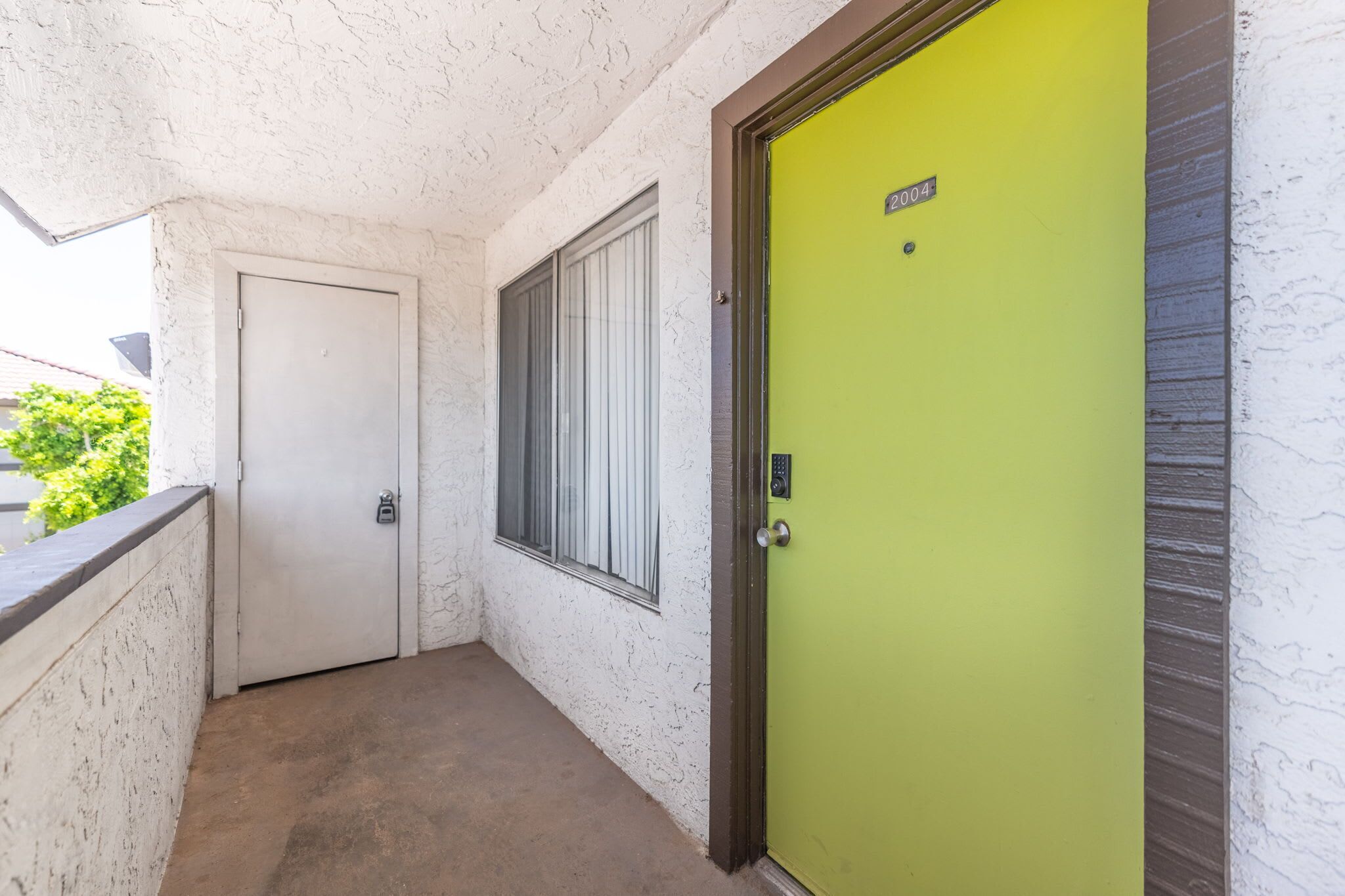 A corridor with a white door and a green door, both with metal handles and a keypad lock.