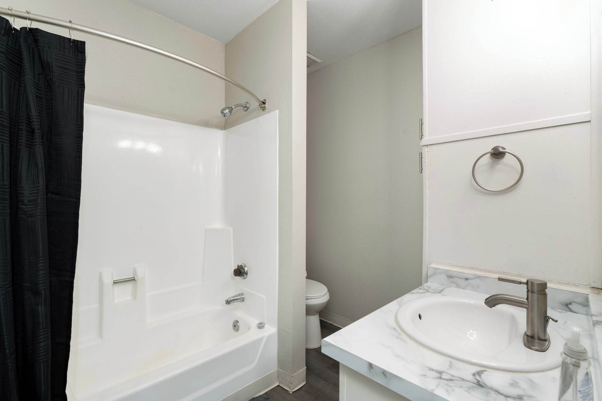 A bathroom with a bathtub, toilet, and sink.