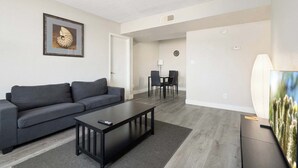 Uma sala de estar moderna com um sofá, mesa de centro e um espaço de jantar com cadeiras.