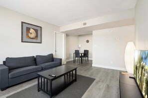 Ein modernes Wohnzimmer mit Sofa, Couchtisch und Essbereich mit Stühlen.