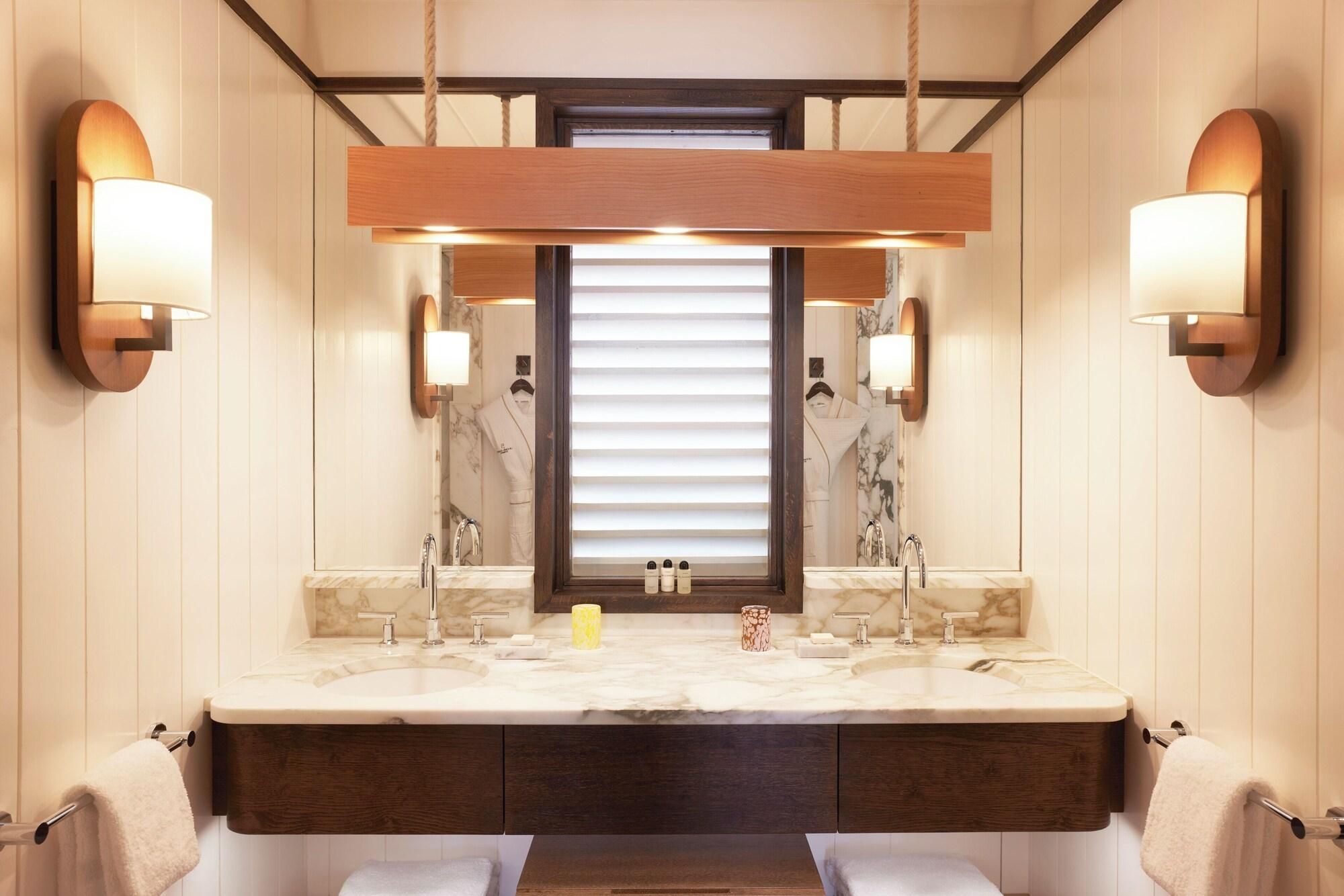 A modern bathroom with a large vanity, dual sinks, and wall-mounted lighting.