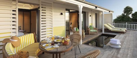 Una terraza con mobiliario exterior, piscina y zona de comedor con productos para el desayuno.