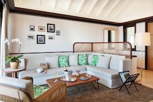 A modern living room with a sectional sofa, a coffee table, a side table with a plant, and a wall with framed pictures.