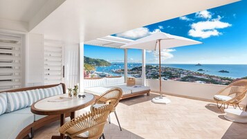 Varanda com vista para o mar, uma cadeira de vime, um sofá e uma mesa.