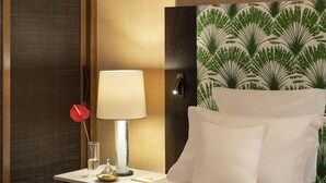 Ett hotellrum med en säng, ett nattduksbord, en lampa och en dekorativ sänggavel.