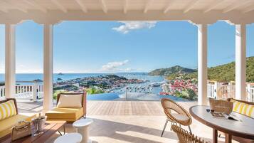 A covered outdoor seating area with a view of a marina and town.