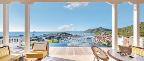 A covered outdoor seating area with a view of a marina and town.