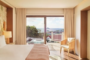 Habitación de hotel con cama, una silla, vista al océano y balcón.