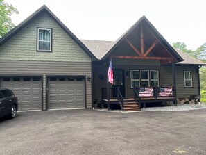 Ein zweistöckiges Haus mit Garage, einer Veranda mit Treppe und einer US-amerikanischen Flagge.