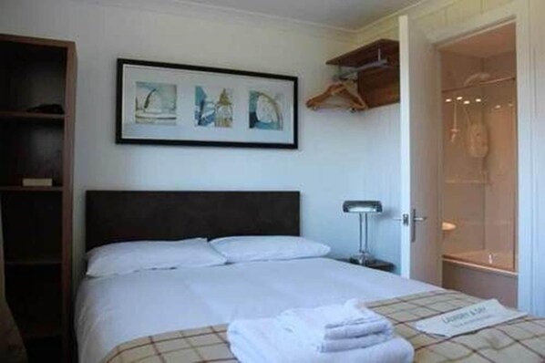 A hotel room with a bed, a bedside table, a wall-mounted artwork, and a shower area.