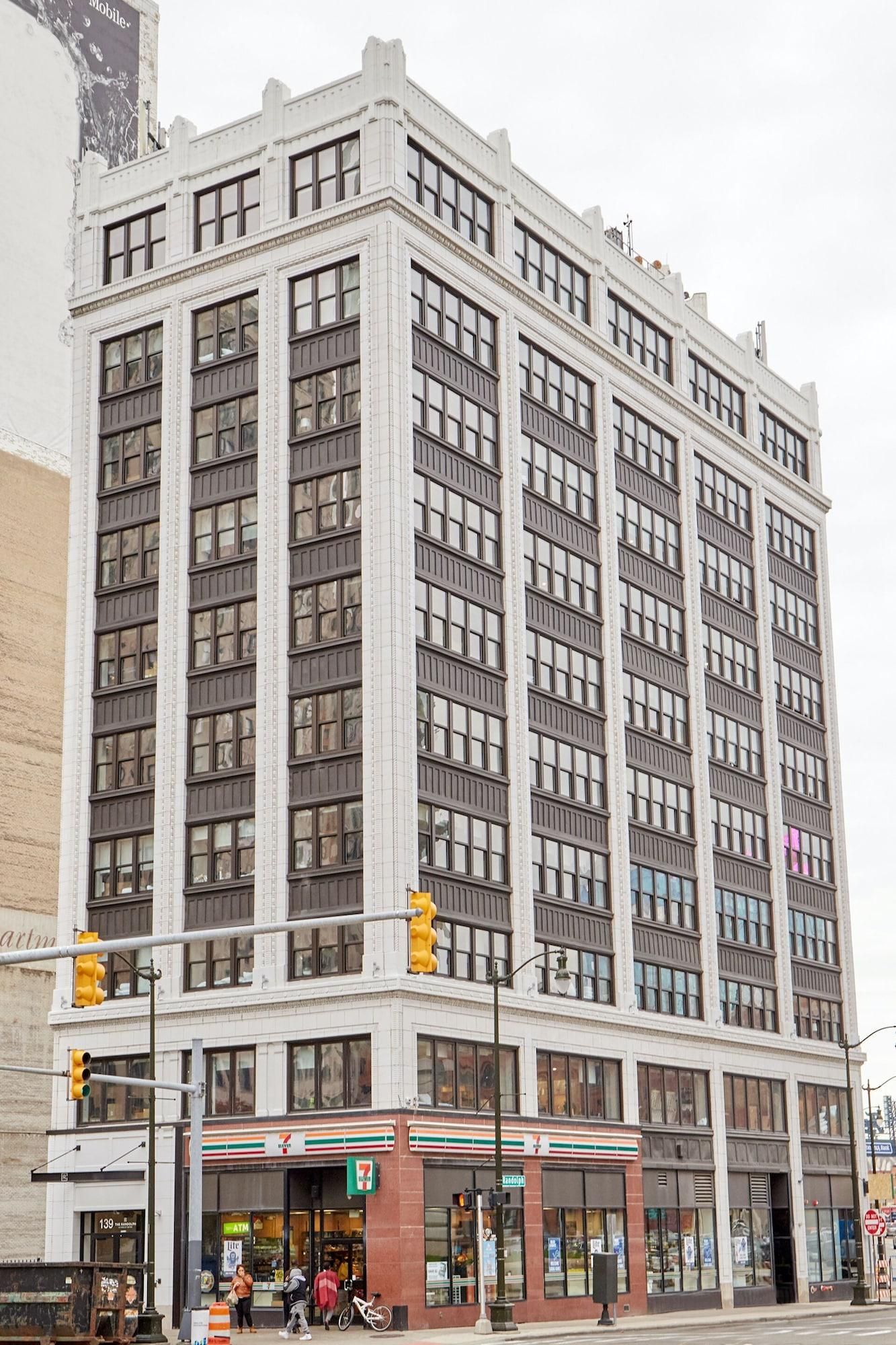 A multi-story building with a corner entrance, large windows, and a 7-Eleven convenience store at the ground level.