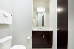 A bathroom with a toilet, a sink, a mirror, and a dark wooden cabinet.