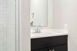 A bathroom with a white sink, a mirror, and a black cabinet.