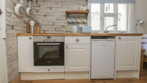 Een kleine keuken met een Bosch oven, vaatwasser en een houten aanrecht.