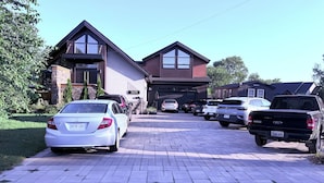 A residential driveway with parked cars and a house with a garage.
