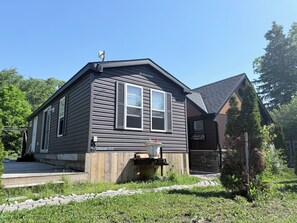 A two-story house with a dark siding exterior, a front porch, and a small garden area.