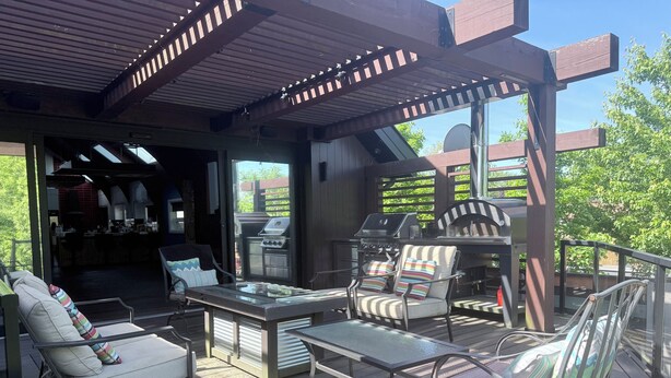 An outdoor patio with a grill, seating, and a view of the backyard.