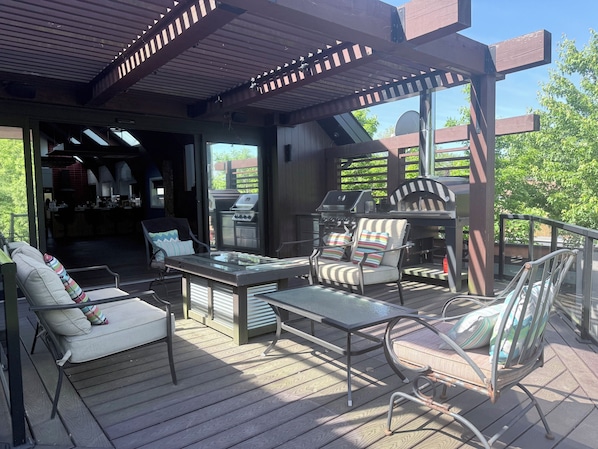 Une terrasse extĂ©rieure Ă©quipĂ©e dâun barbecue, de siĂšges et offrant une vue sur le jardin.