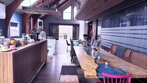 A modern kitchen with a long wooden island, a dining area with a glass table, and a view of a pool.