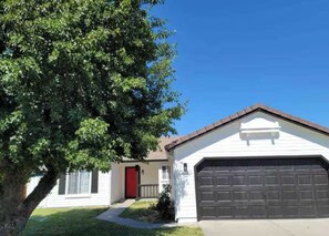 A single-story house with a garage, a red door, and a tree in the foreground. - Spacious Single Level Home with 2 King Beds Sleeps 8 (Salida)