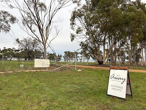 A signboard with 'Tiny Away' and 'Avondale Heights' text, a fenced area, and trees.
