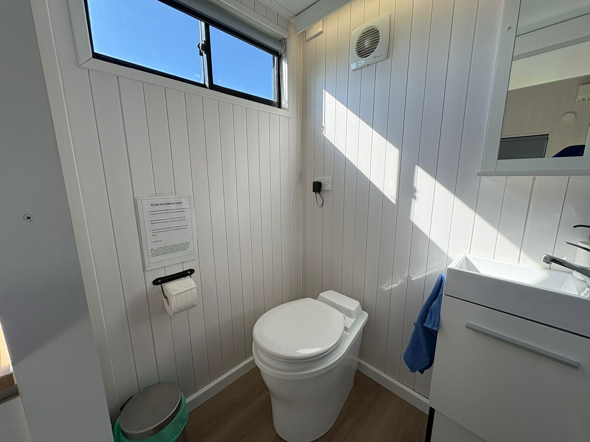 A small, compact bathroom with a toilet, a sink, a mirror, and a window.