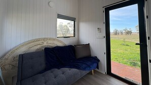 Una habitación con una cama, una ventana y una puerta que da a un espacio exterior.