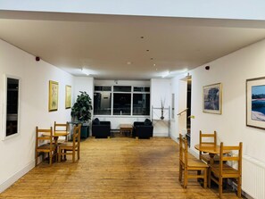 A room with a wooden floor, white walls, a large window, and several chairs. - Chatsworth Hotel (Skegness)