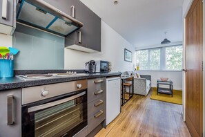Eine moderne Küche mit Einbauofen, Mikrowelle und Kaffeemaschine. Ein Essbereich mit einer Couch und einem kleinen Tisch.