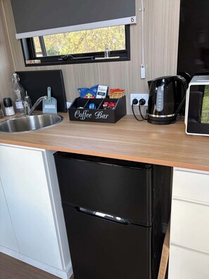 A compact kitchen with a coffee bar, a kettle, and a microwave.