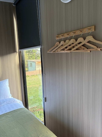 A bedroom with a bed, a window, and a wooden hanger rack.. Whispering Wetlands by Tiny Away