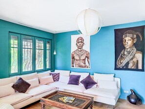 A room with teal walls, a white sofa, a coffee table, and two large framed artworks. - Grande Bastide by Interhome (Mougins)