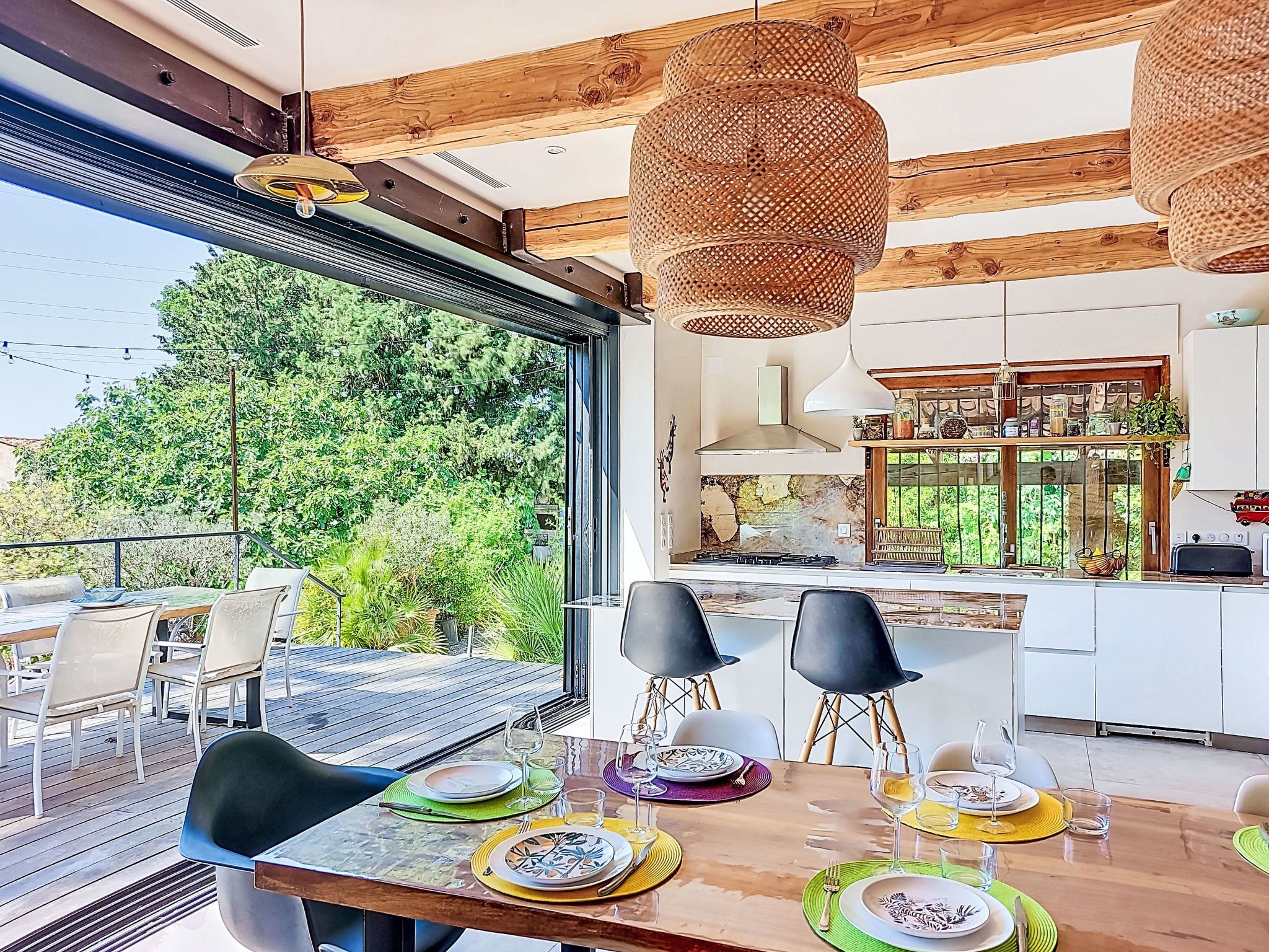 Une cuisine moderne dotée d’une grande fenêtre, d’un coin repas avec des chaises et d’une vue sur la verdure.