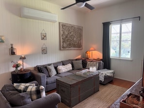A living room with a sofa, a coffee table, a lamp, a fireplace, and a window with a view.