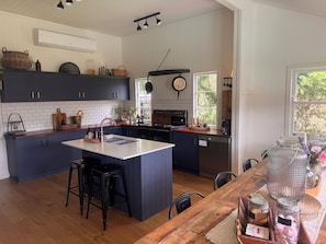 A kitchen with a central island, dark blue cabinets, a white countertop, and a wooden dining table with chairs.
