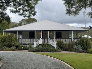 A two-story house with a covered porch and a gravel driveway.