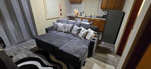 A compact room with a sofa, a small kitchen area, and a visible door. - COZYHUB -B (philipsburg)
