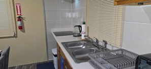 A kitchen with two sinks, a fire extinguisher, a kettle, and a trash bin. - COZYHUB -B (philipsburg)