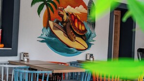 Un murale raffigura una tartaruga su una tavola da surf con un tramonto e una palma.