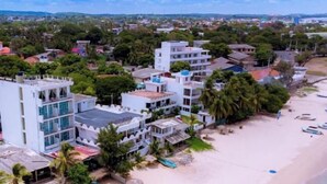 Un hotel costero con varias edificaciones, una playa y palmeras.
