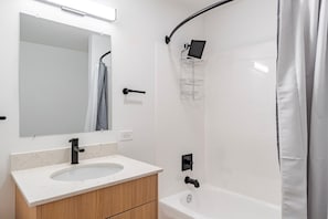 A modern bathroom with a sink, mirror, shower, and a clear shower tray. - Blueground | Denny Triangle, view, nr Seattle Art Museum (Seattle)