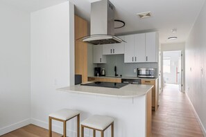 Cuina moderna amb una illa central, electrodomèstics integrats i un disseny minimalista.